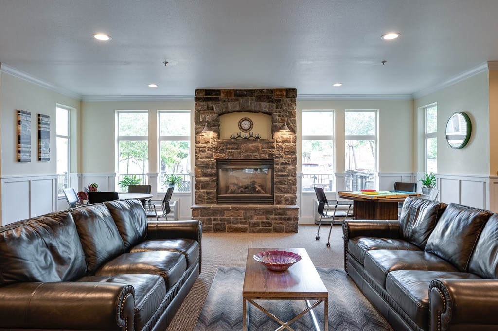 A living room with a stone fireplace and leather couches.