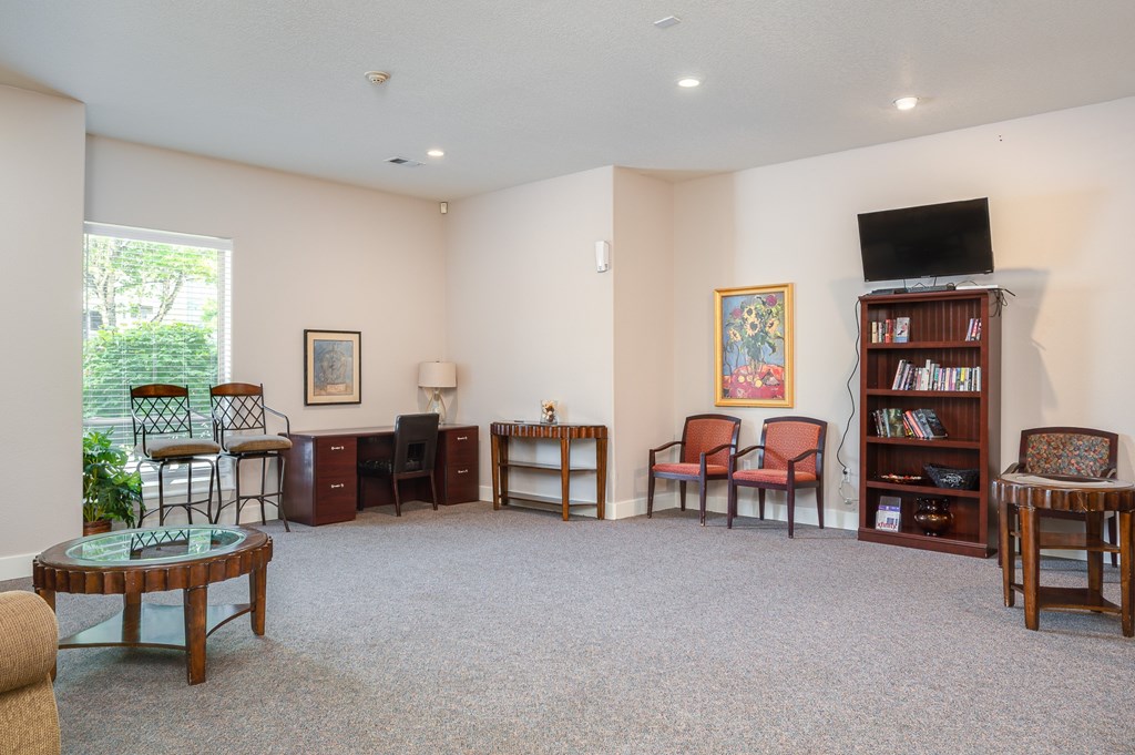 A living room with a carpeted floor and a bookshelf.