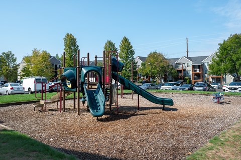A playground with a green slide and a red and green play structure.