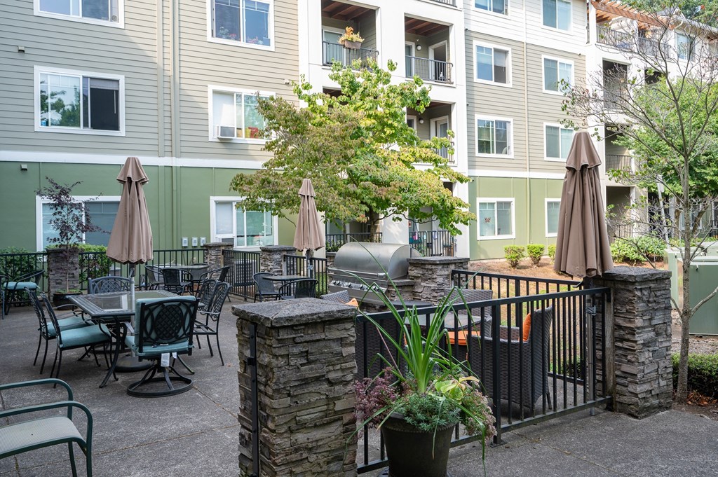 A patio with tables and chairs and umbrellas in front of a building.