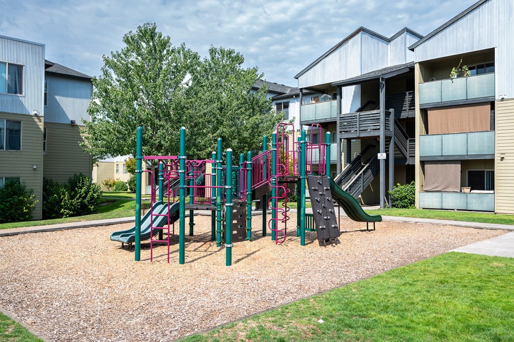 A playground with a green slide and a red and green play structure.
