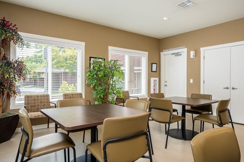 A dining room with a table surrounded by chairs.