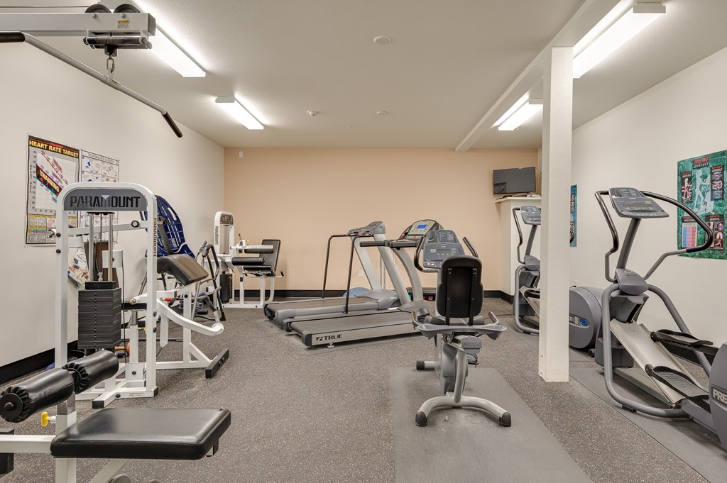 A gym with a variety of equipment including treadmills, weights, and exercise machines.