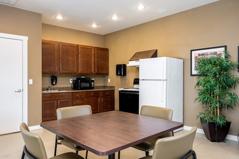 A kitchen with a table and chairs in the foreground and a refrigerator in the background.