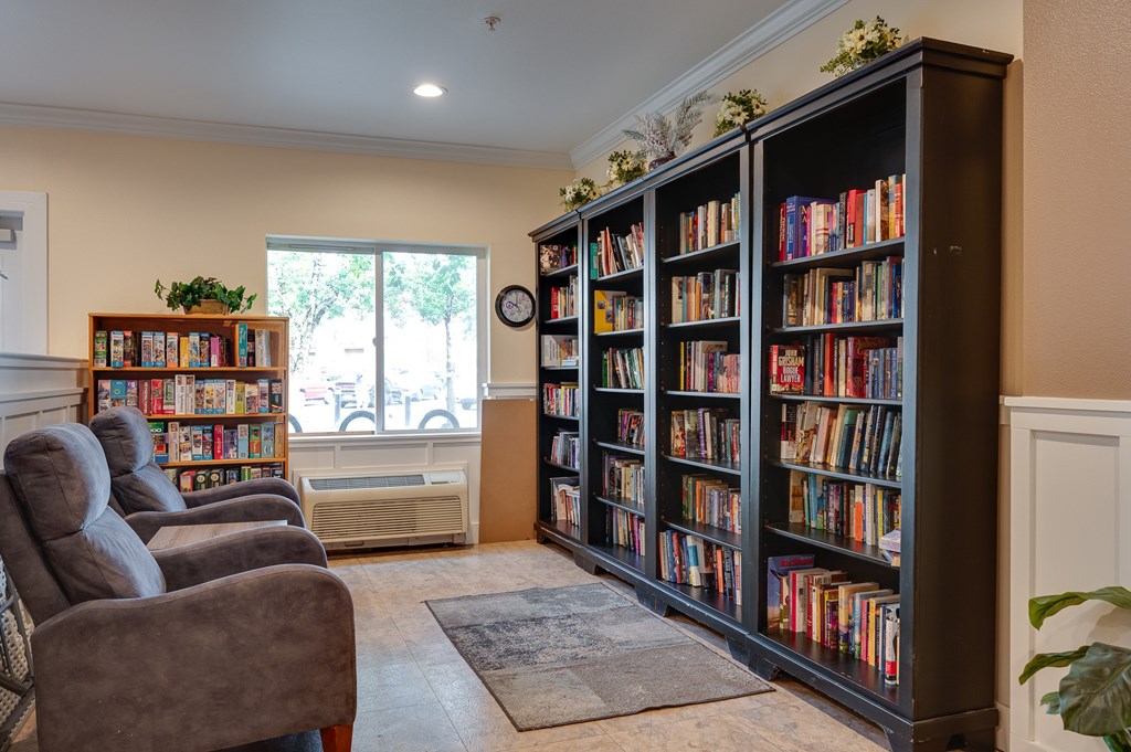A room with a large bookshelf filled with books and a grey sofa.