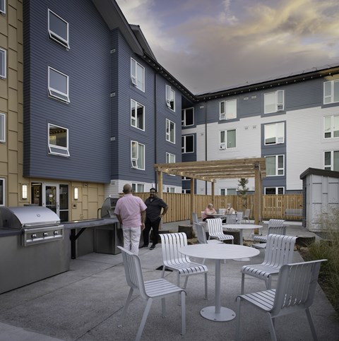 A man in a pink shirt is standing on a patio.