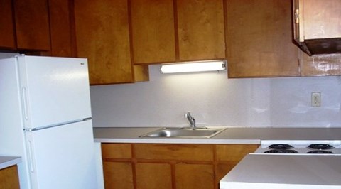 A kitchen with wooden cabinets and a white fridge.