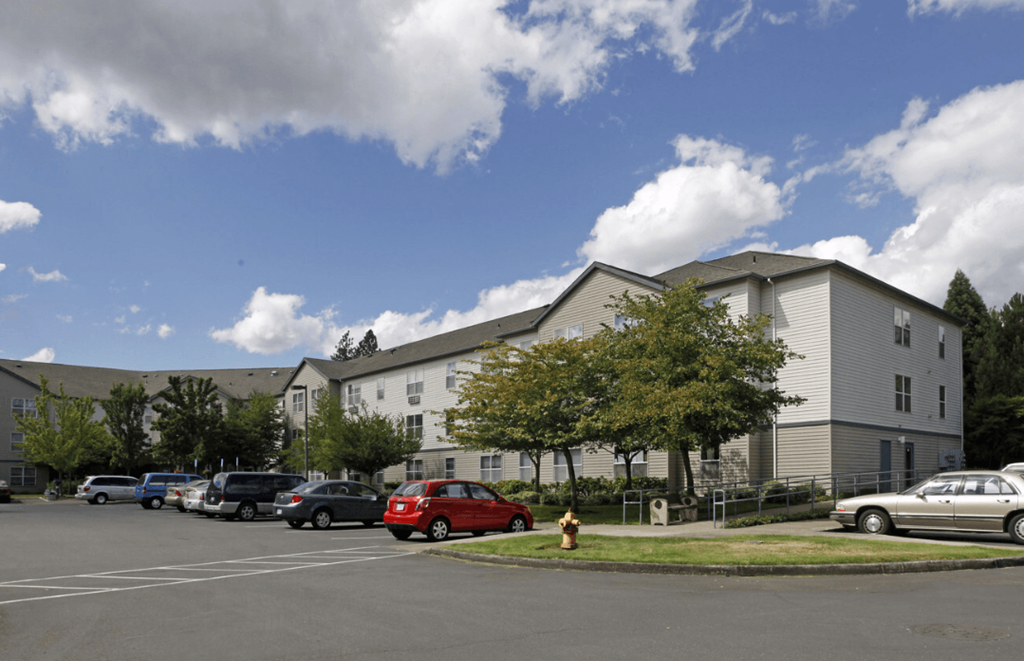 A parking lot with cars and a fire hydrant in front of a building.