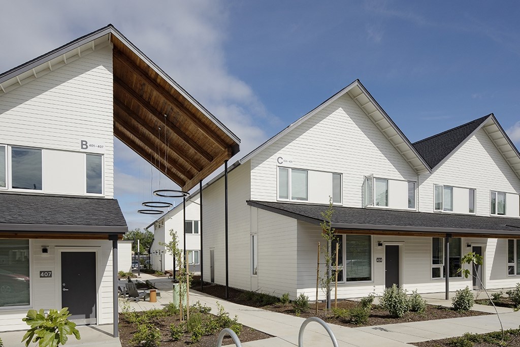 A modern white house with a brown roof and a black door.