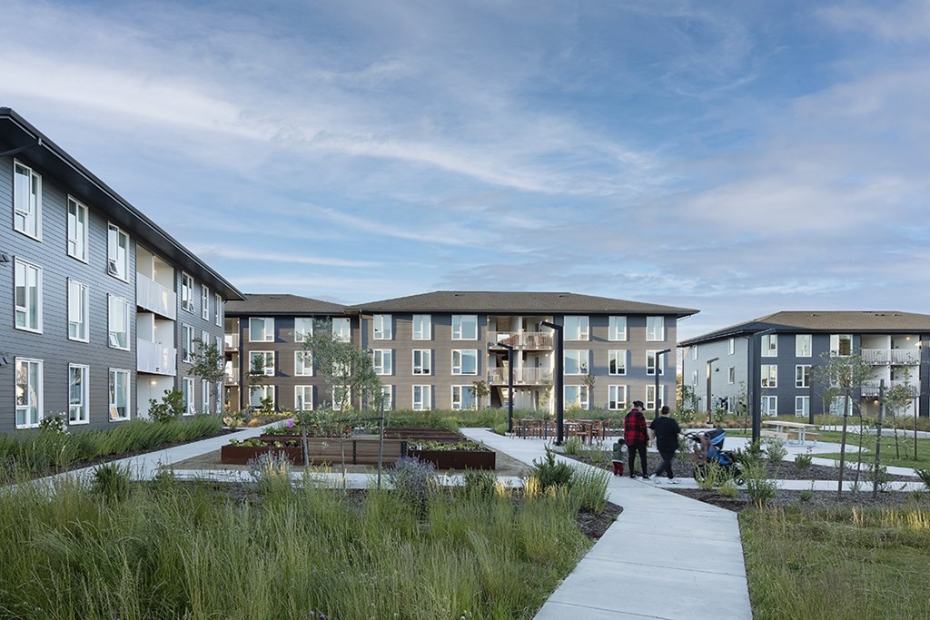 A group of people are walking down a path in front of apartment buildings.