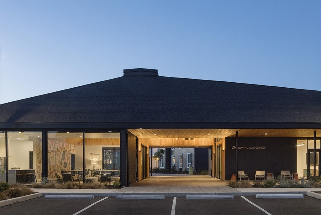 A modern building with a dark roof and glass windows is labeled