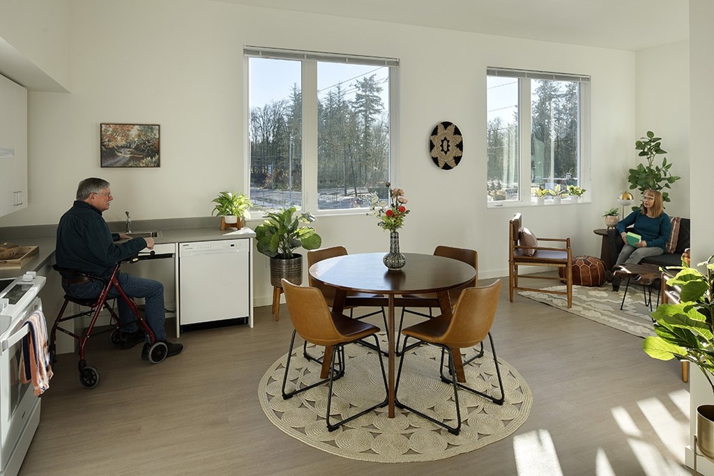 A man in a wheelchair is sitting at a table in a kitchen.
