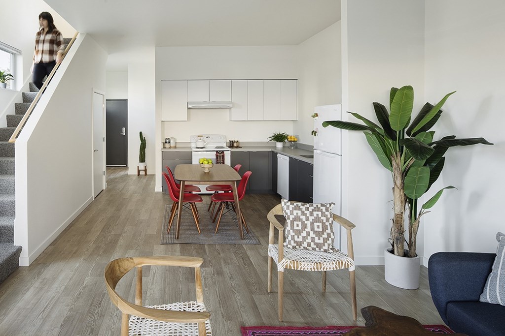 A woman is standing on a staircase in a modern kitchen and living room.