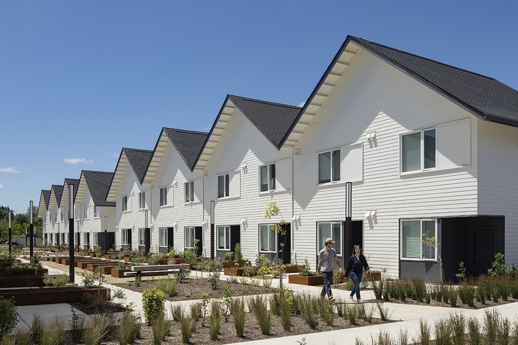 A row of white houses with a garden in front.