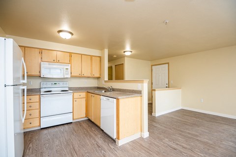 an empty kitchen with white appliances and wooden cabinets