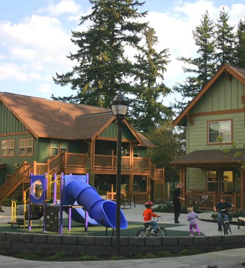 A playground with a purple slide in front of a green building.