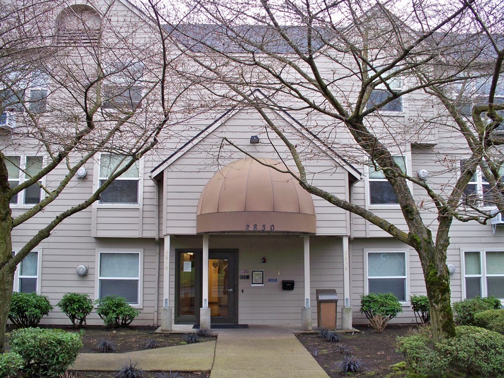 the front of a white house with a sidewalk and trees