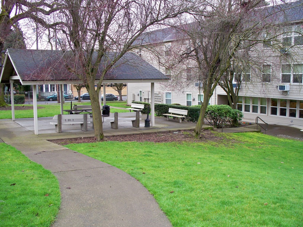 a park with benches and a pavilion in front of a building