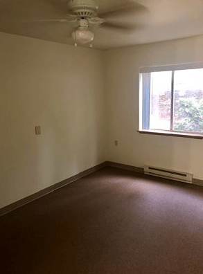 an empty room with a window and a ceiling fan
