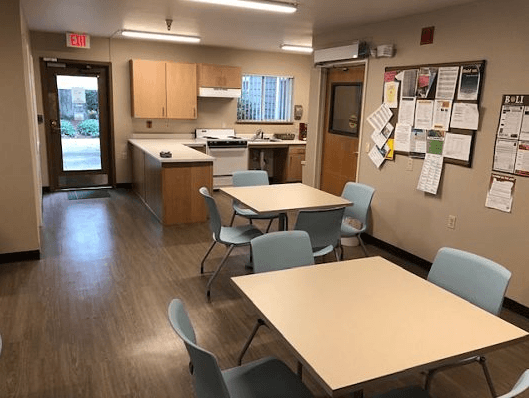 a multipurpose room with tables and chairs and a kitchen