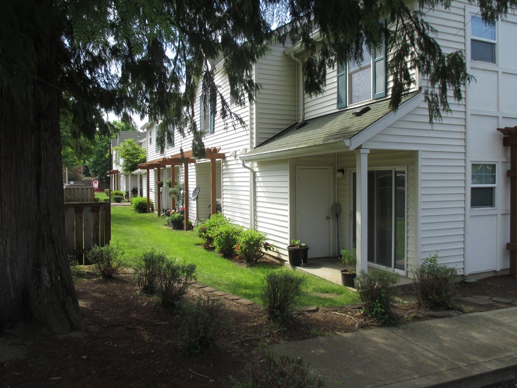a row of white houses with a lawn and trees