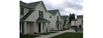 a row of houses with white siding and green roofs