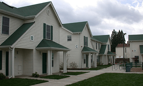 a row of houses with white siding and green roofs