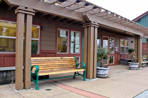 A wooden bench with green legs is in front of a building.