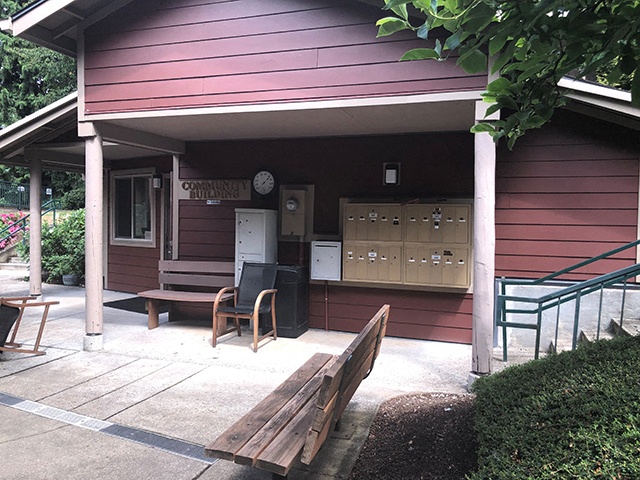a porch in front of a red house with a wooden bench