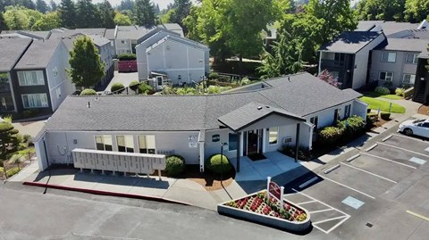 A parking lot with a building and a flower bed in front.