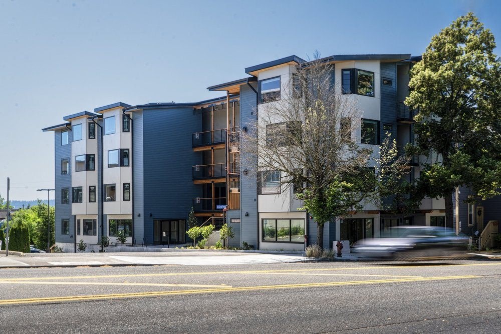 a car driving past an apartment building on a city street