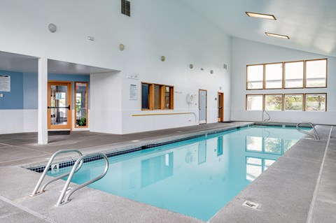 a swimming pool in a large room with a pool table and chairs