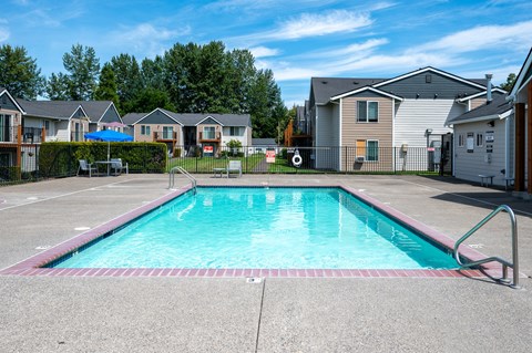 A swimming pool in a residential area with houses in the background.