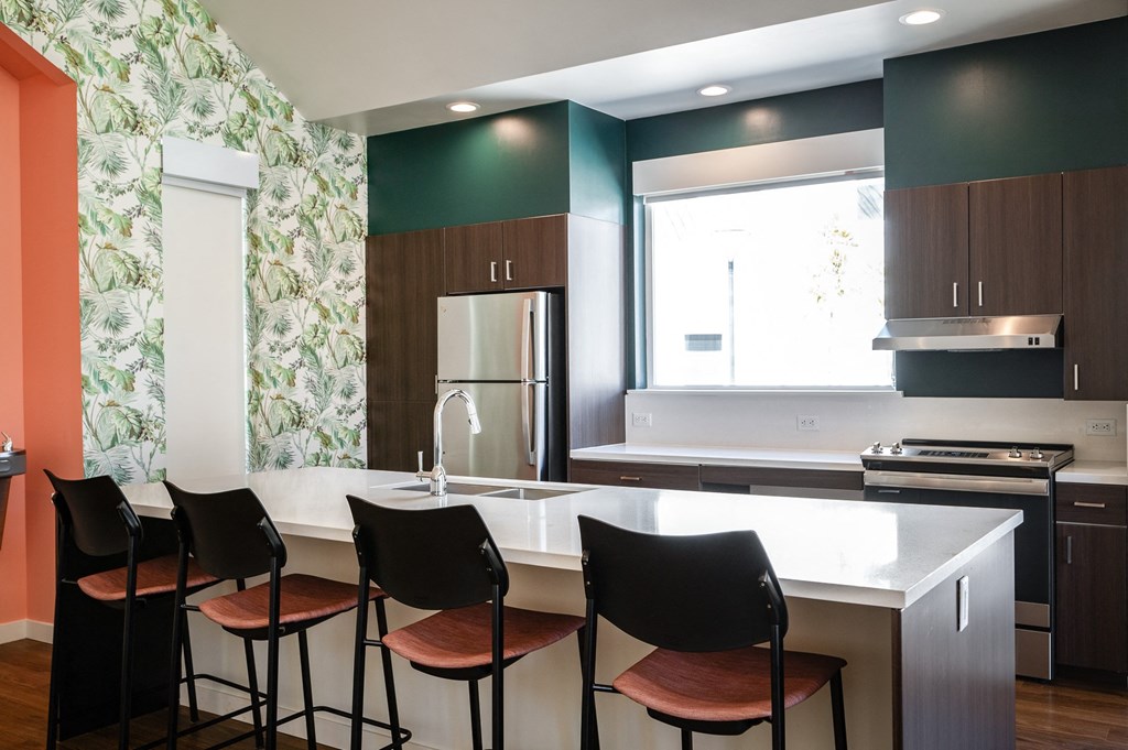 a kitchen with a white counter top and black chairs
