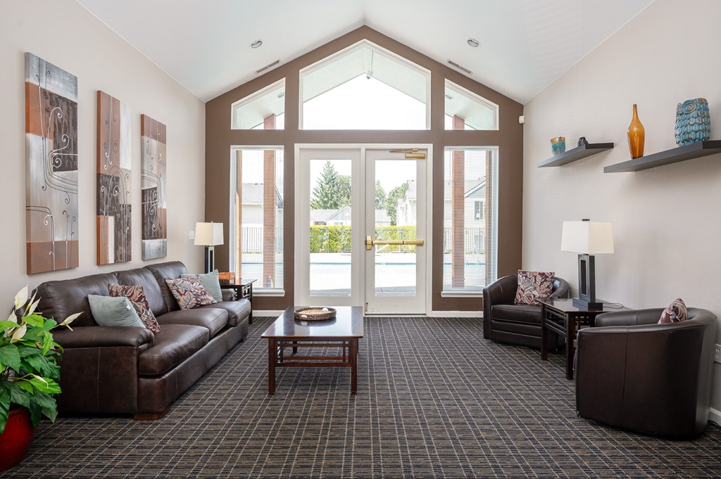 A living room with a brown couch, a coffee table, and a large window.