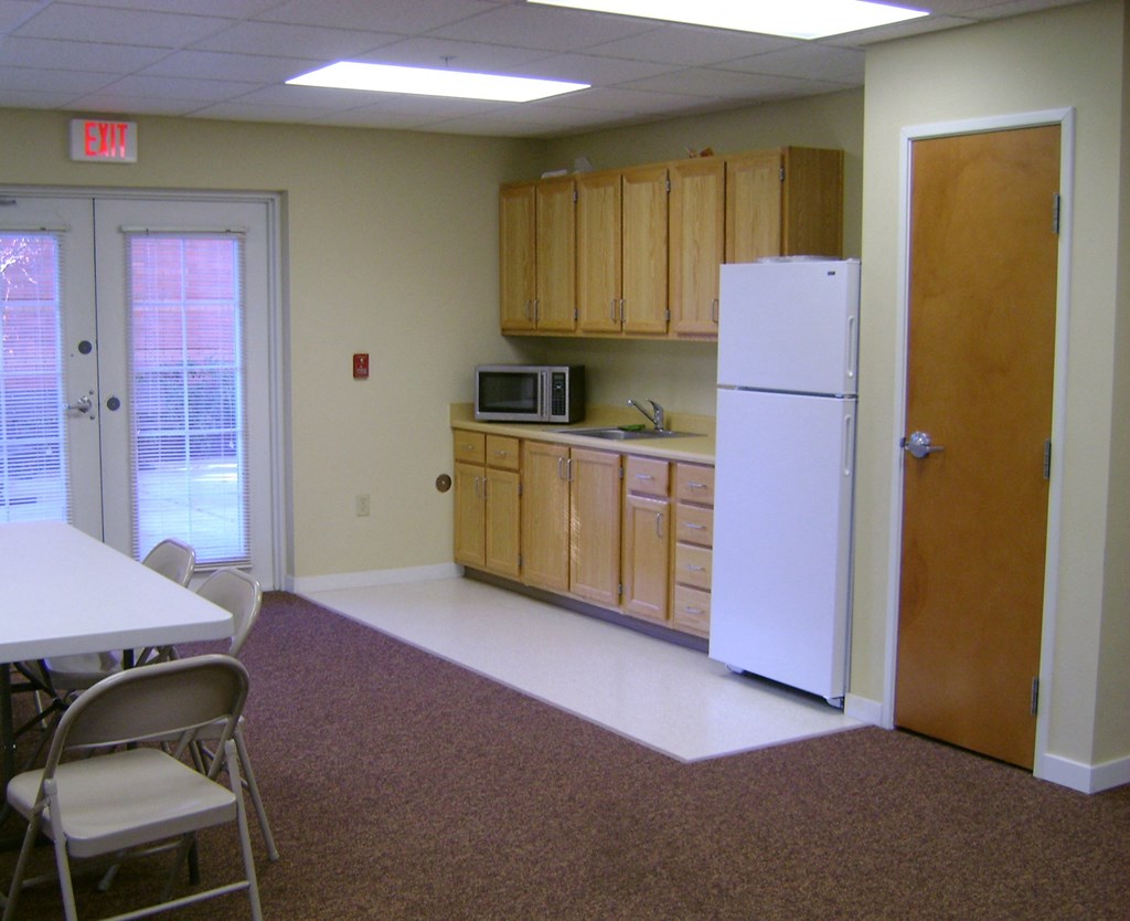 a kitchen with a refrigerator and a table and chairs