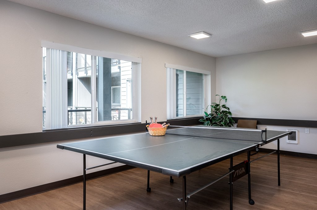 an empty room with a ping pong table and windows