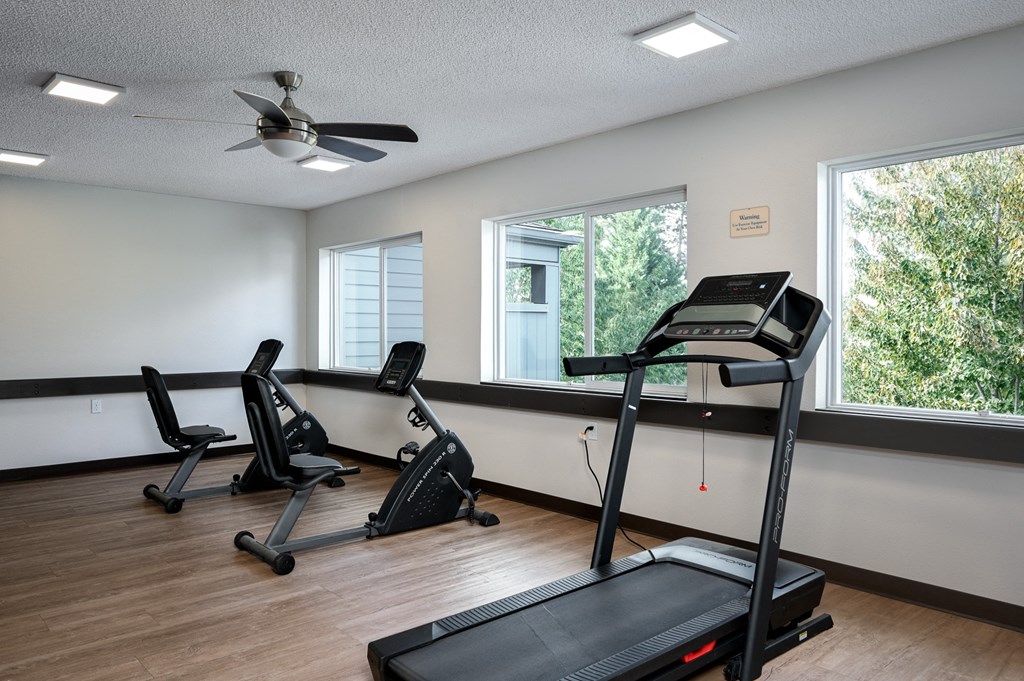 the gym has plenty of exercise equipment and a large window