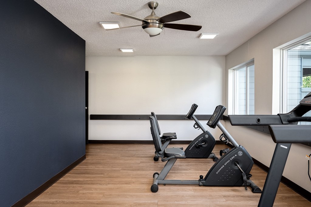 the gym with two desks and two chairs and a ceiling fan