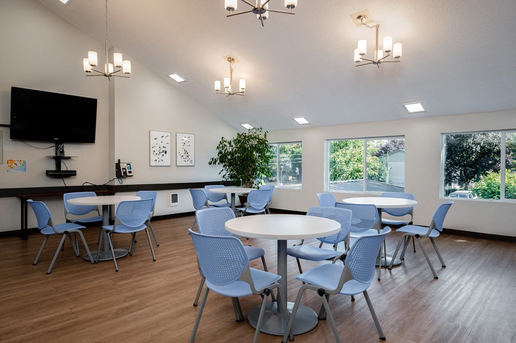 a community room with tables and chairs and a television