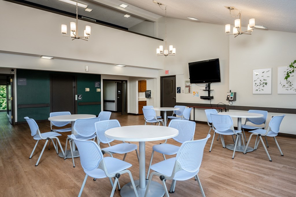 a dining room with white tables and chairs and a television