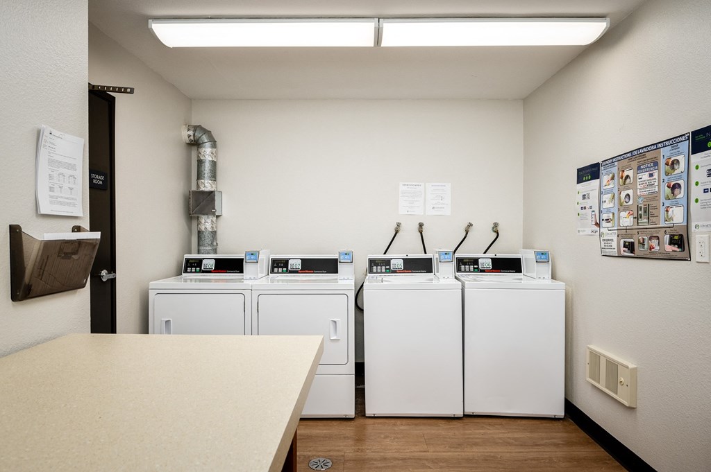 four washers and dryers in a laundry room with a counter and a door