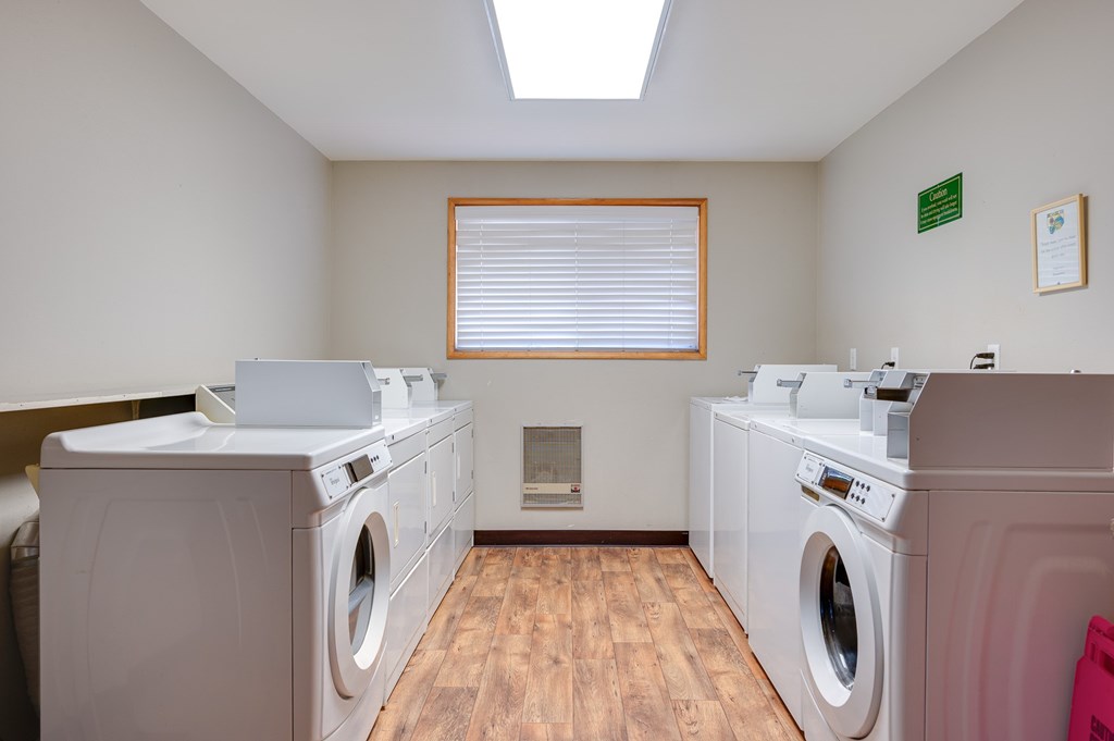A laundry room with two washing machines and a window with blinds.
