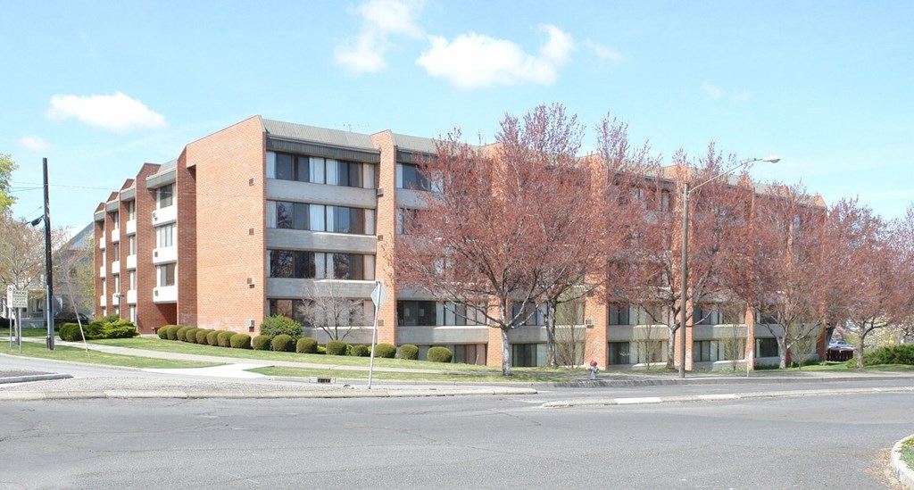 A large brick building with a tree in front of it.