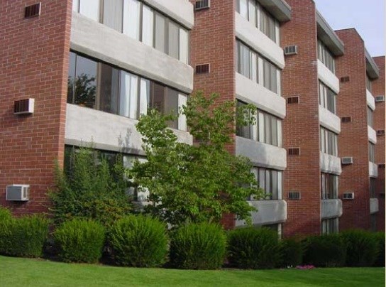 A red brick building with white trim and a tree in front.
