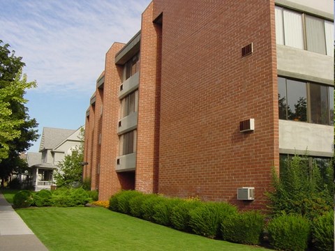 A red brick building with a green lawn in front.