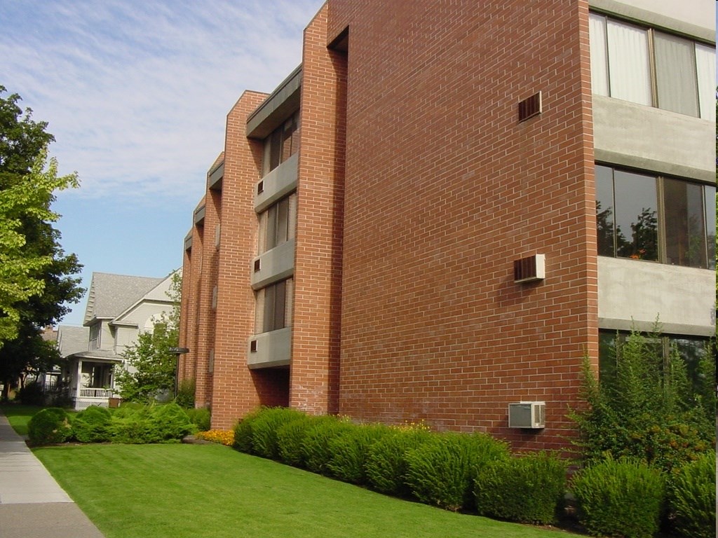 A red brick building with a green lawn in front.