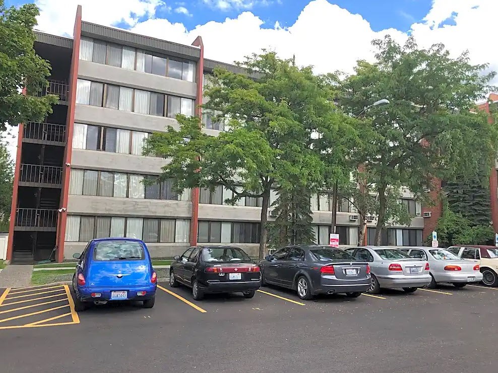 A blue car is parked in a parking lot in front of a building.
