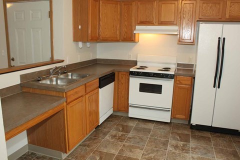 A kitchen with wooden cabinets and a white stove top oven.
