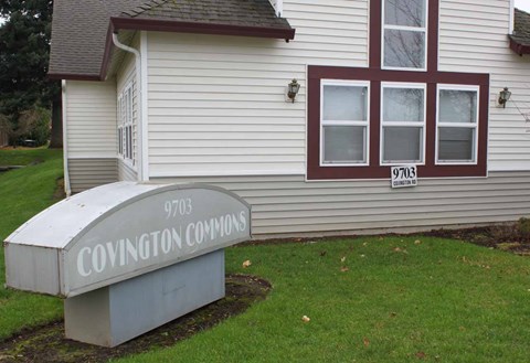A sign for Covington Commons sits in front of a house.